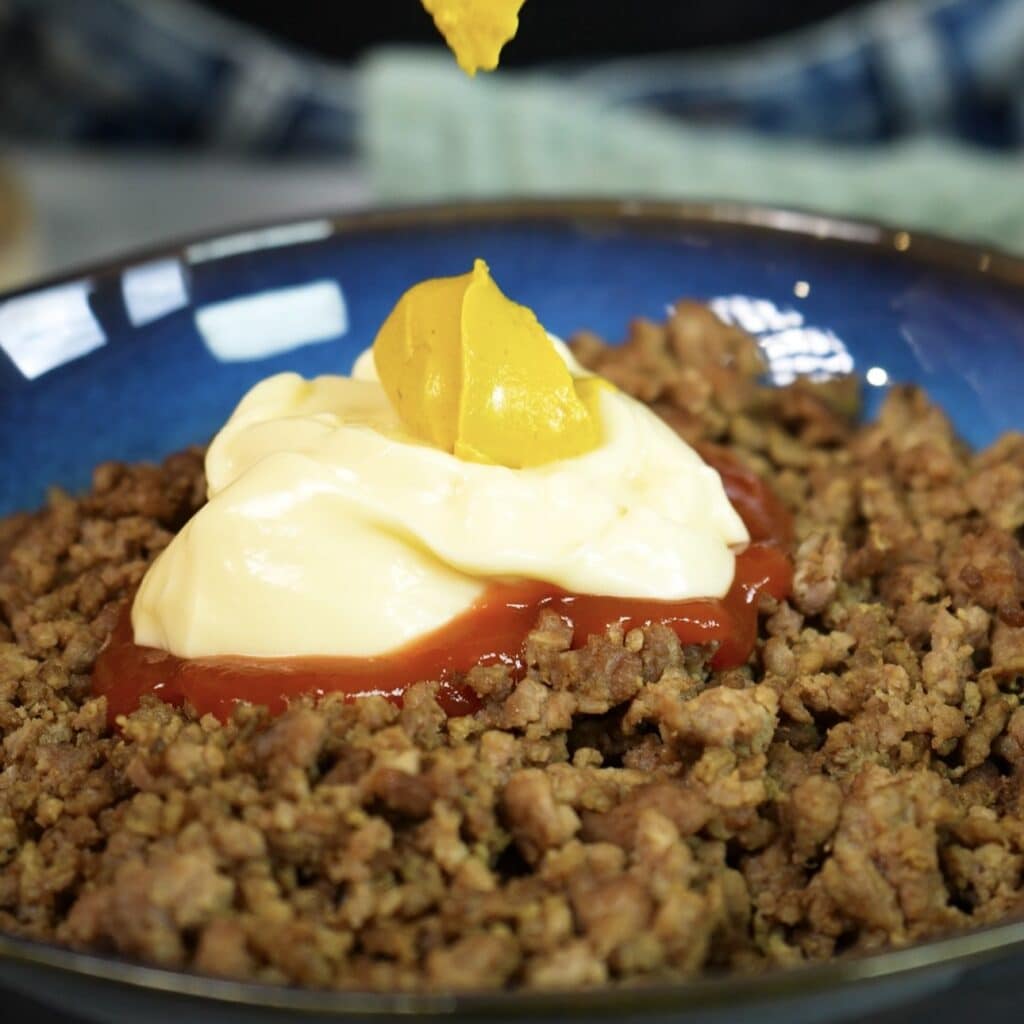 Mixing cooked minced beef with mayonnaise, ketchup and mustard for rice paper cheeseburger rolls