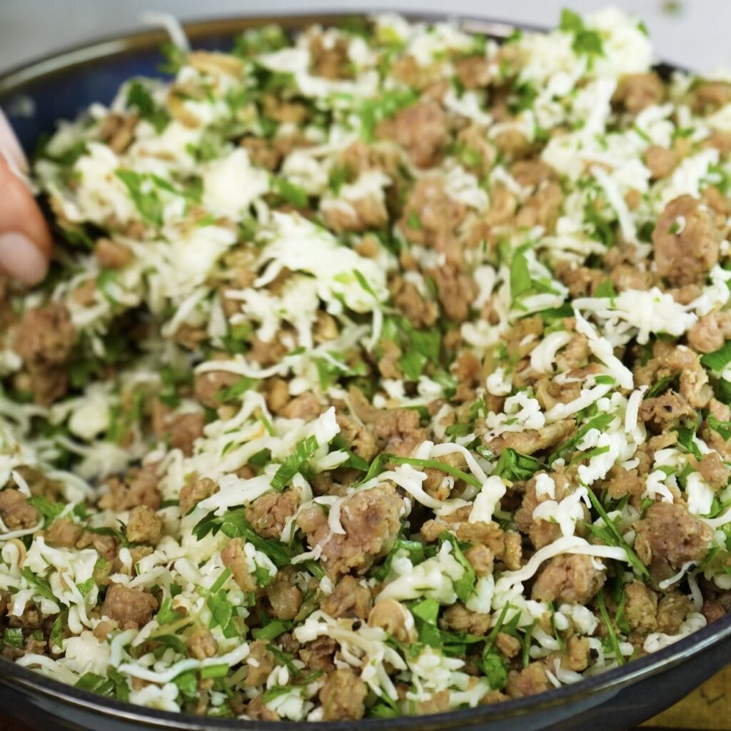 Mixing cooked minced beef with grated mozzarella and chopped coriander for cheesy beef filo swirls.