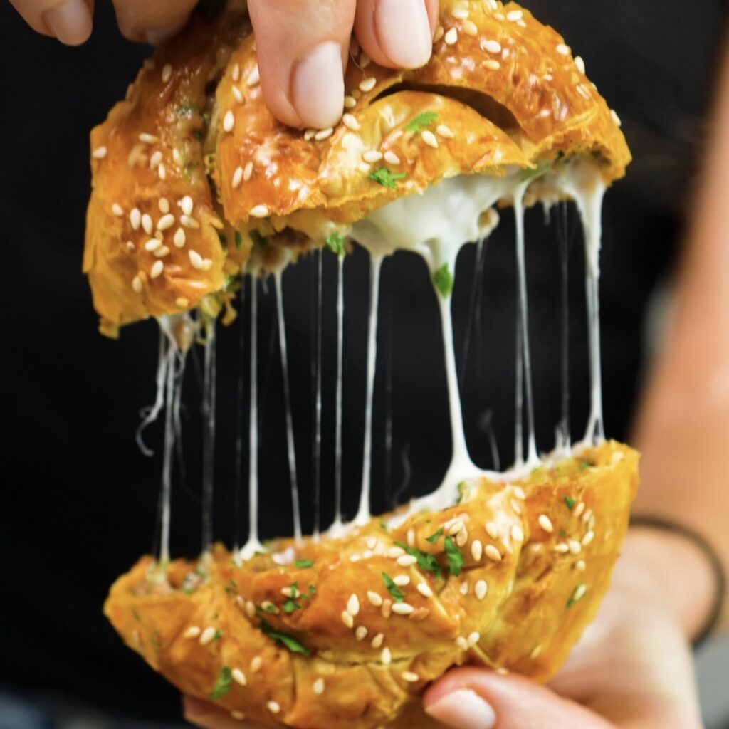 Cheesy beef filo swirl cut in half showing melted mozzarella cheese pull.