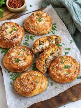 Cheesy beef filo swirls served on a wooden board.