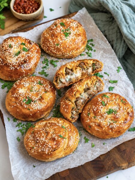 Cheesy beef filo swirls served on a wooden board.