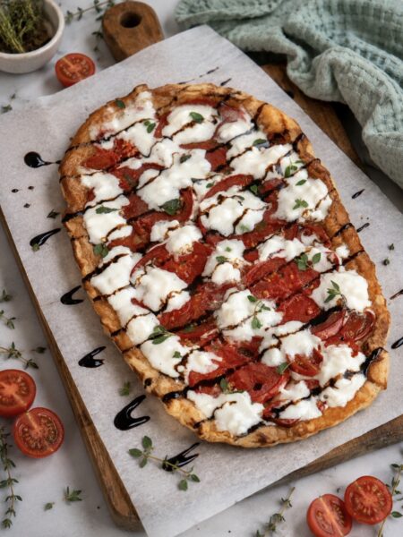 Tomato and stracciatella upside-down tart served on a wooden board.