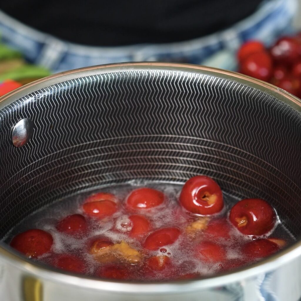 Ingredients for homemade cherry sauce in a saucepan with cherries, honey, cornstarch, water and lemon juice