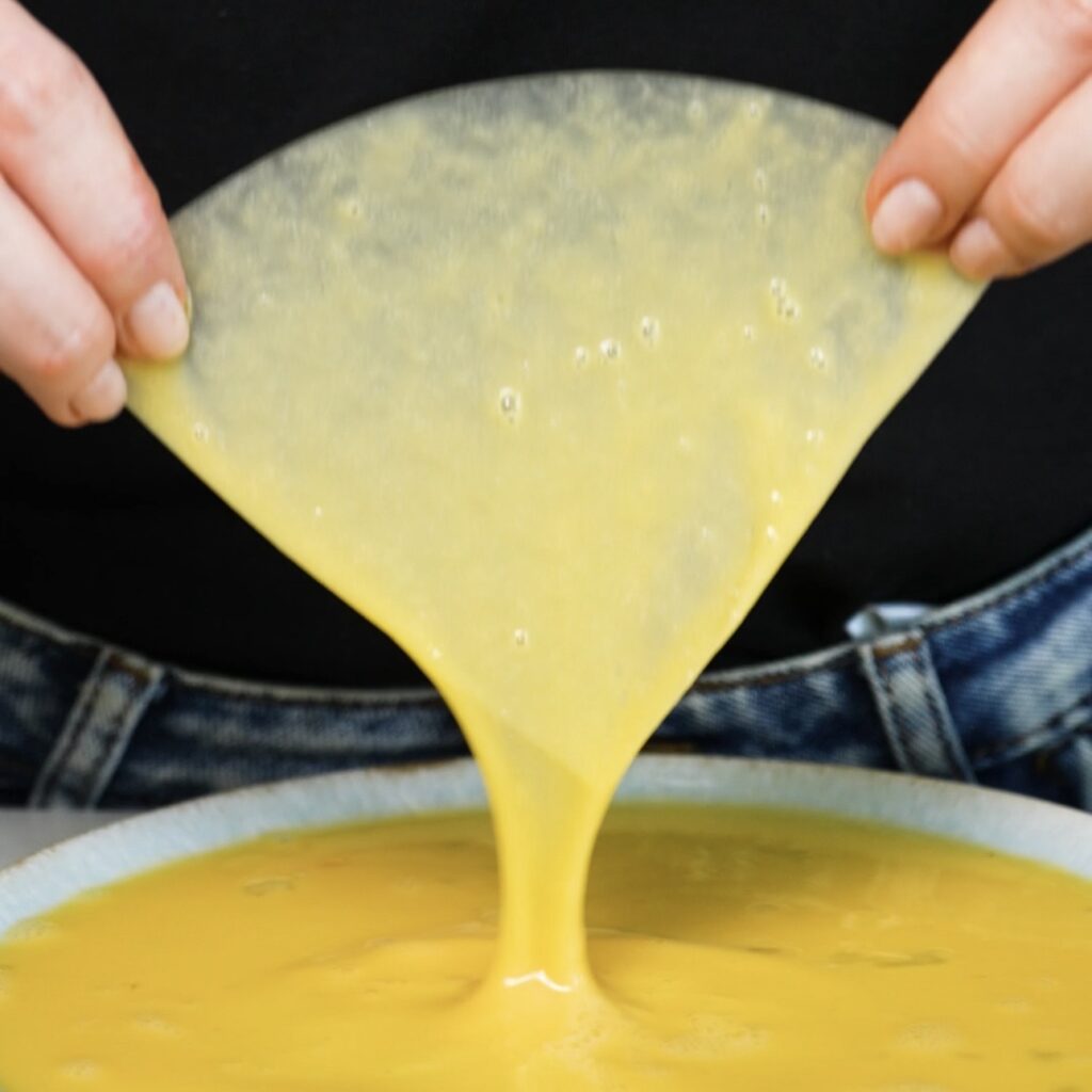 Dipping a quarter piece of rice paper into the egg mixture.