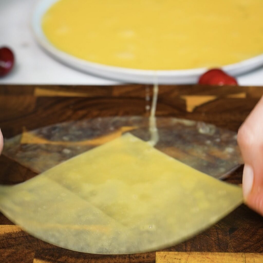 Two pieces of rice paper placed on a wooden board before adding the filling.