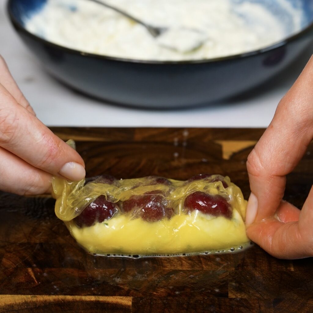 Sealing the rice paper edges around the ricotta and cherry filling.