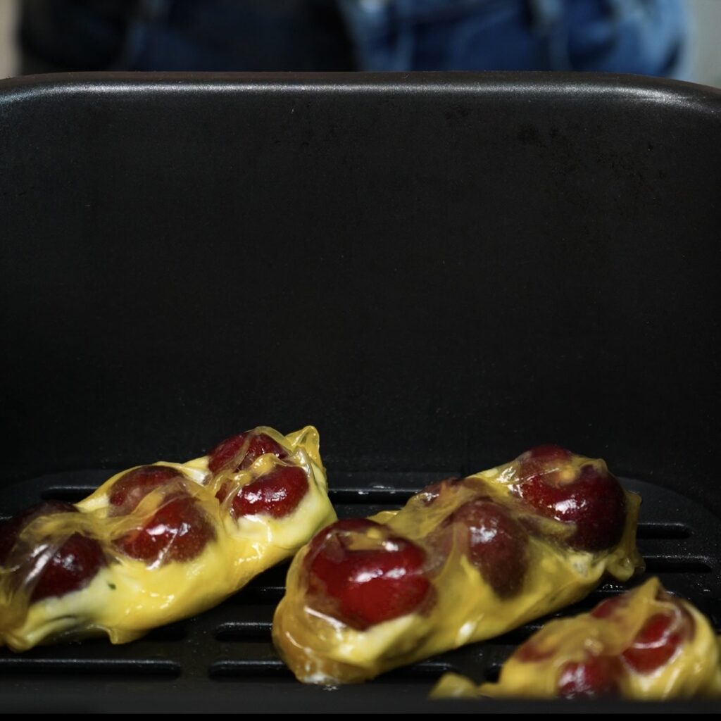 Cherry ricotta rice paper dumplings arranged in the air fryer basket before cooking.