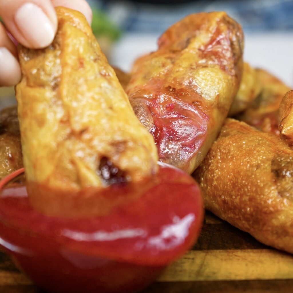 Dipping a cherry ricotta rice paper dumpling into homemade cherry sauce.