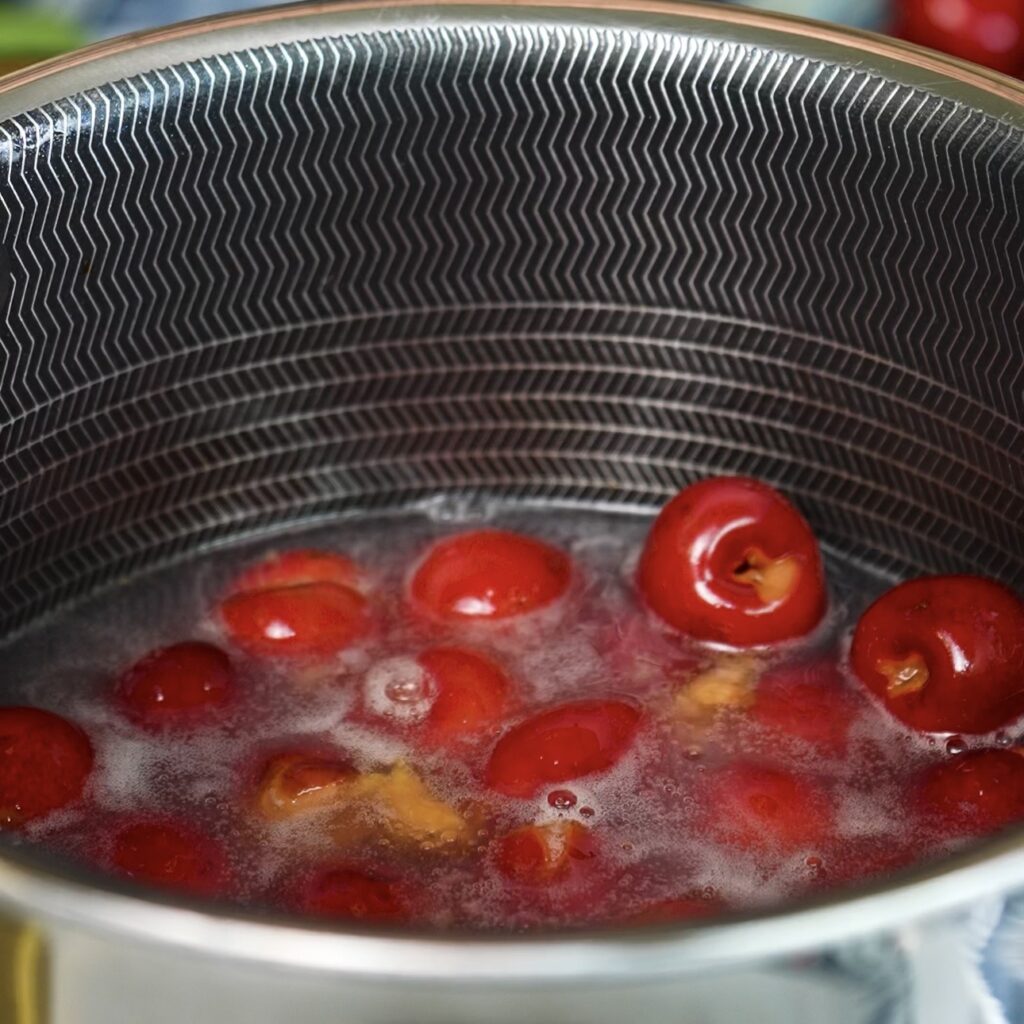 Cherries cooking in a saucepan with honey, lemon juice and cornstarch for homemade cherry sauce.