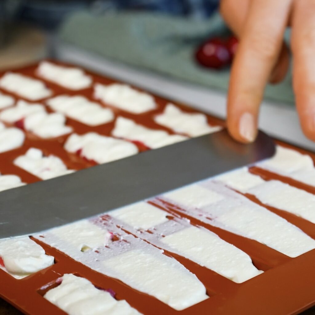 Smoothing the top of the cottage cheese mixture in a silicone mould before freezing.