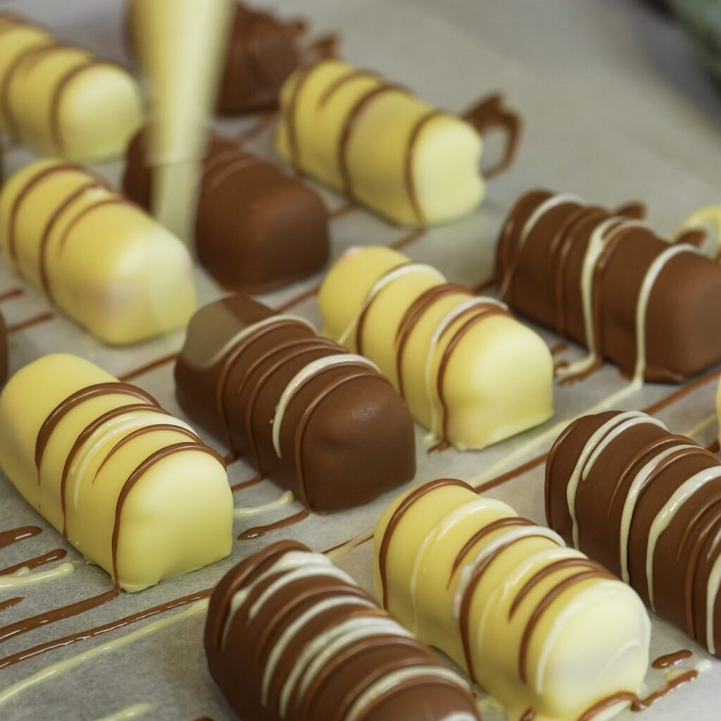 Chocolate-coated cherry cottage cheese bars being drizzled with extra melted chocolate.