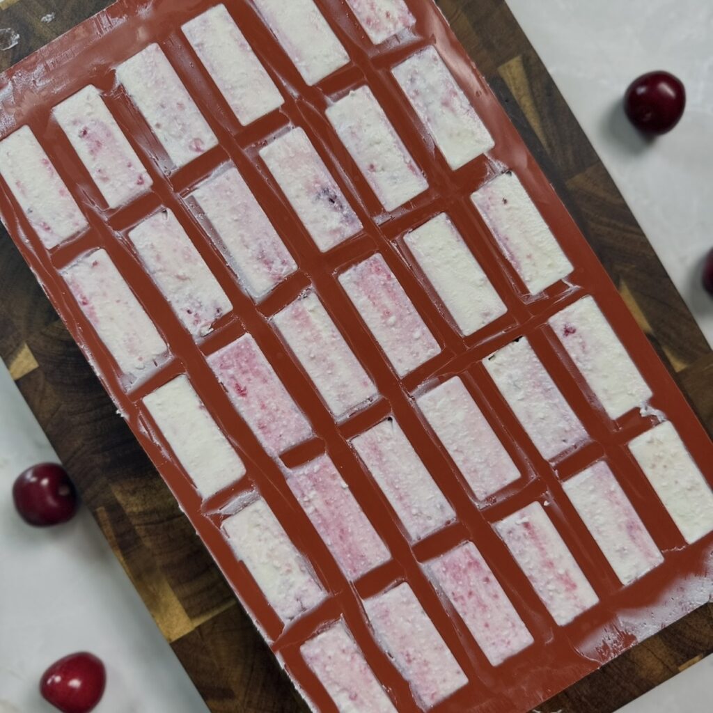 Silicone mould filled with cottage cheese mixture and cherry sauce before freezing.
