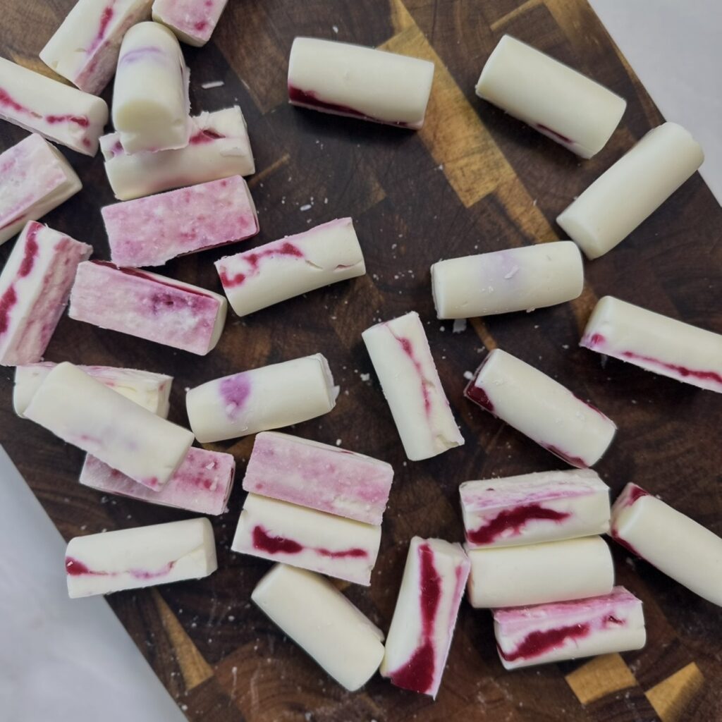 Frozen Cherry Cottage Cheese Bars lying on a wooden board after being removed from the silicone mould.