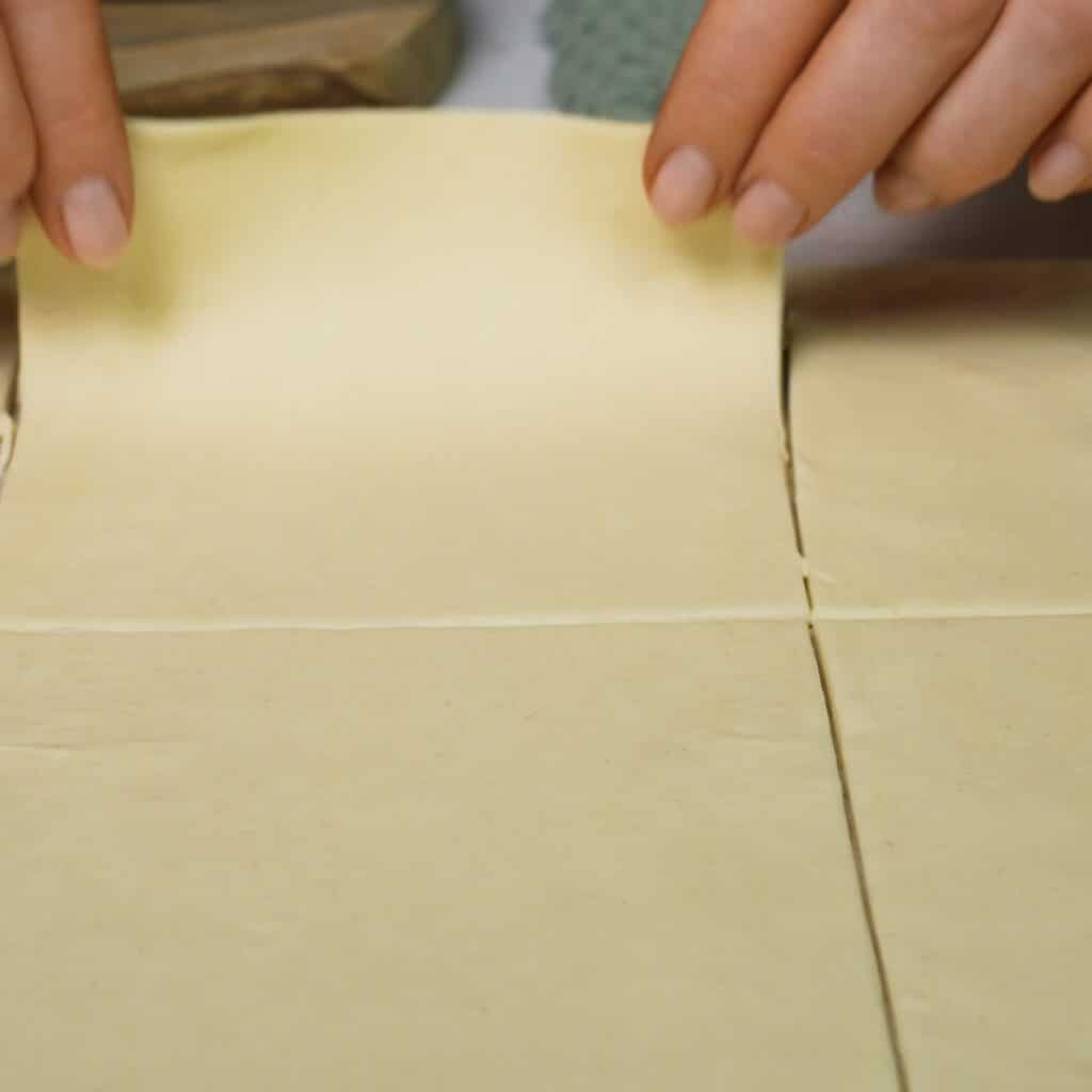 Puff pastry sheet being cut into six equal squares for Cherry and Pistachio Yogurt Puffs.