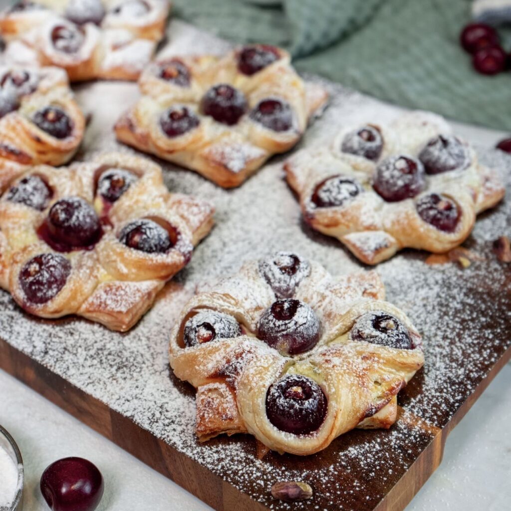 Cherry and Pistachio Yogurt Puffs served on a wooden board.