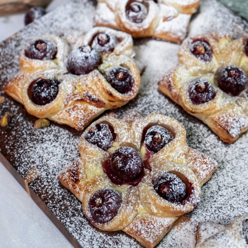 Cherry and Pistachio Yogurt Puffs served on a wooden board.