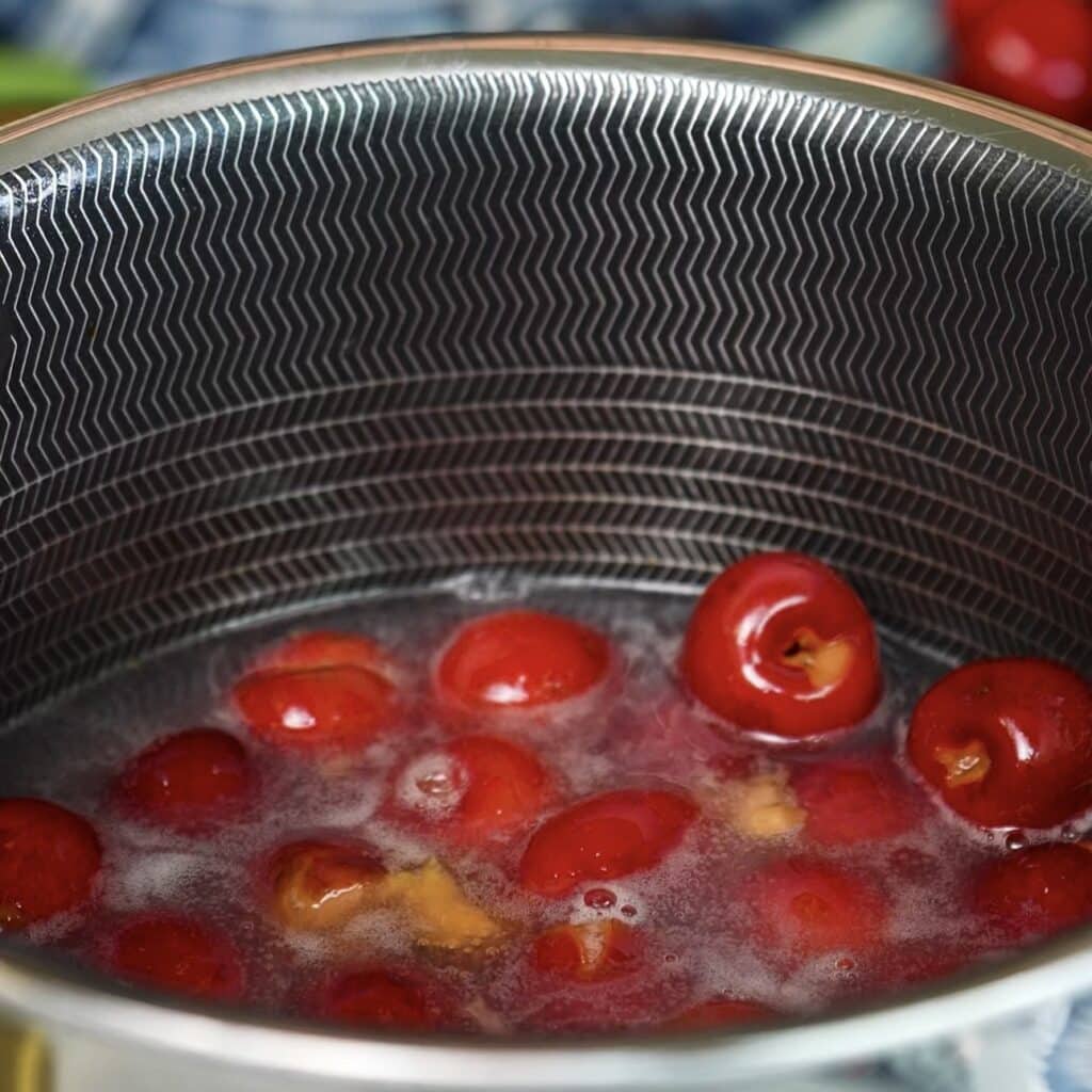 Homemade cherry sauce simmering in a saucepan until thickened
