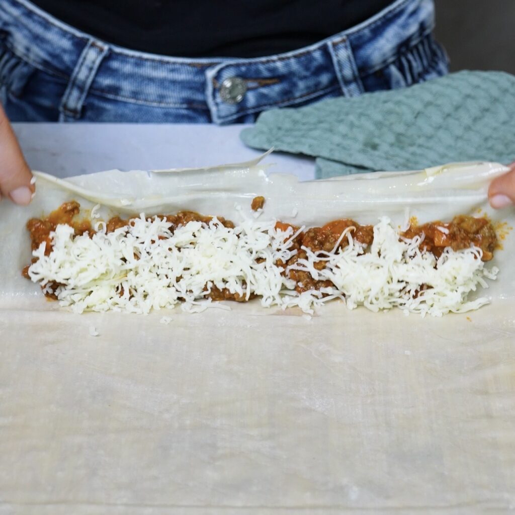 Folding filo pastry over the beef ragù and mozzarella filling to enclose it