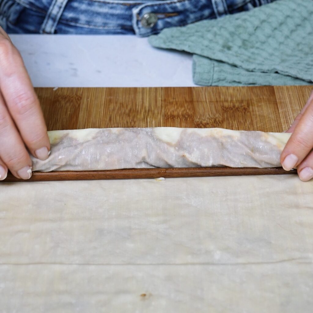 Placing a chopstick beside the covered beef and mozzarella filling before rolling the filo pastry