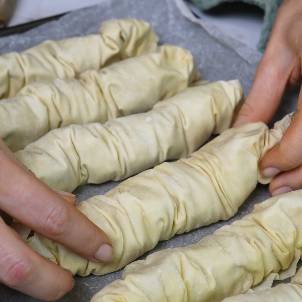 Placing the crinkled beef and mozzarella filo rolls on a prepared baking tray