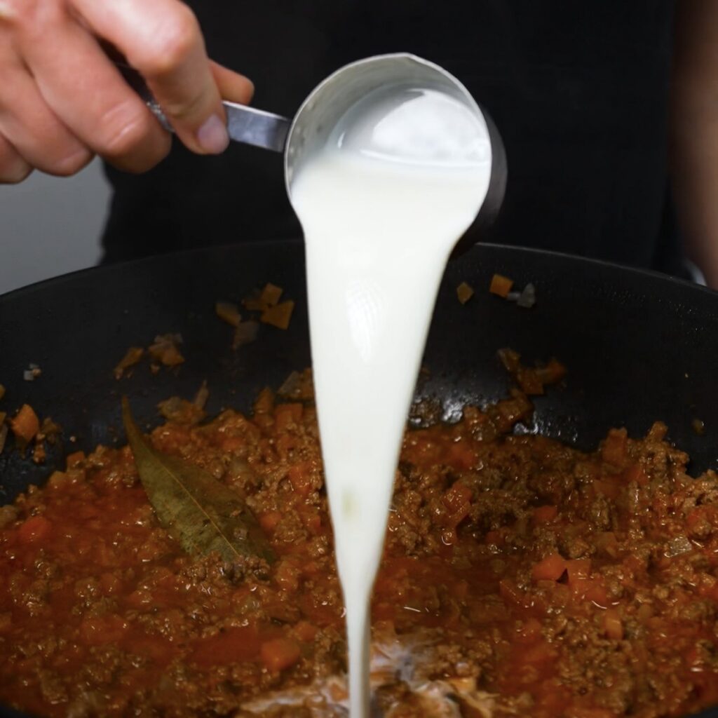 Adding milk to the beef ragù towards the end of cooking