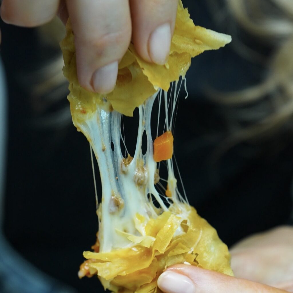 Breaking open a Cheesy Beef Ragù Filo Roll to reveal the melted mozzarella filling