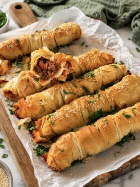 Baked Cheesy Beef Ragù Filo Rolls served on a wooden board