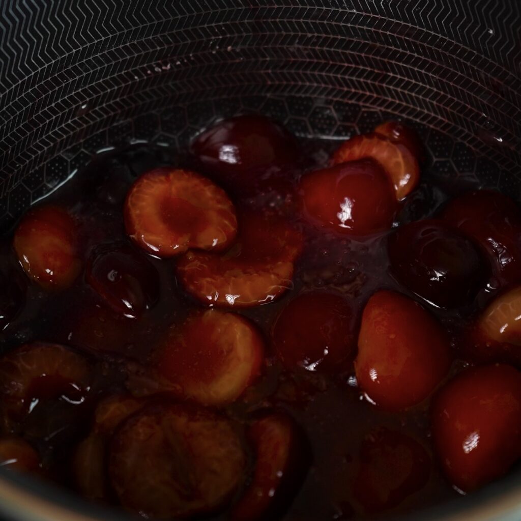 Cherries simmering in a saucepan to make homemade cherry compote