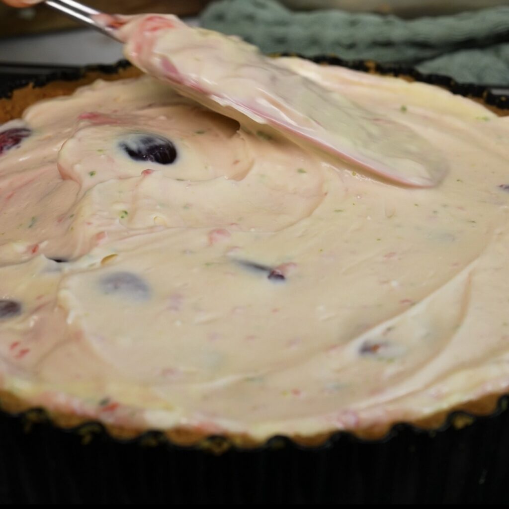 Cheesecake filling added to the biscuit base and smoothed with a spatula