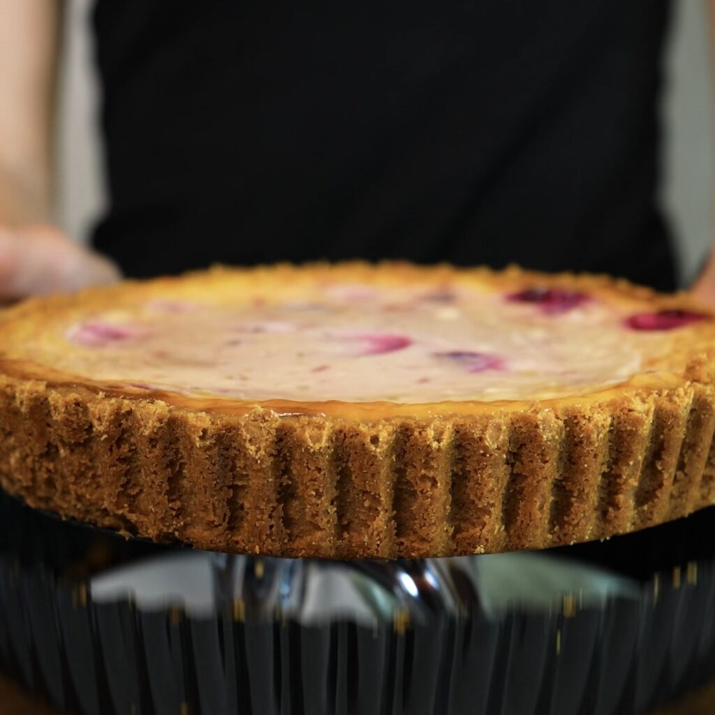 Removing the chilled cherry cheesecake from a loose-bottomed tart tin