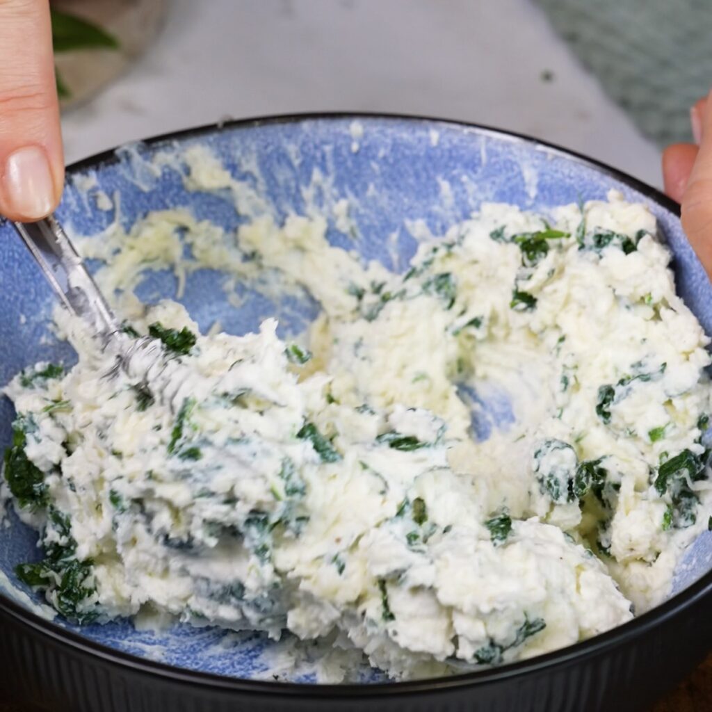 Mixing the four-cheese and spinach filling in a bowl.