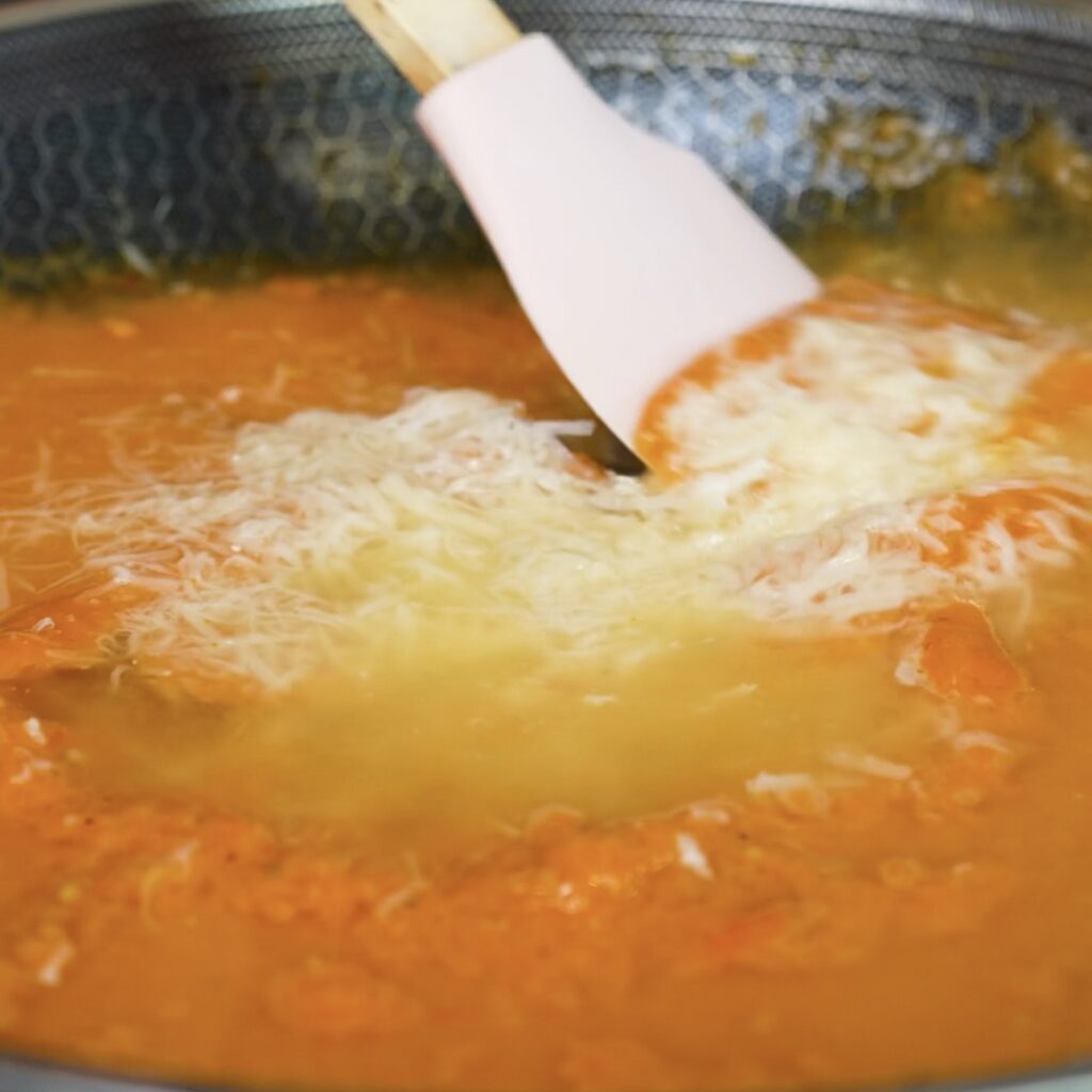 Stirring grated Parmesan into the roasted tomato and garlic sauce.