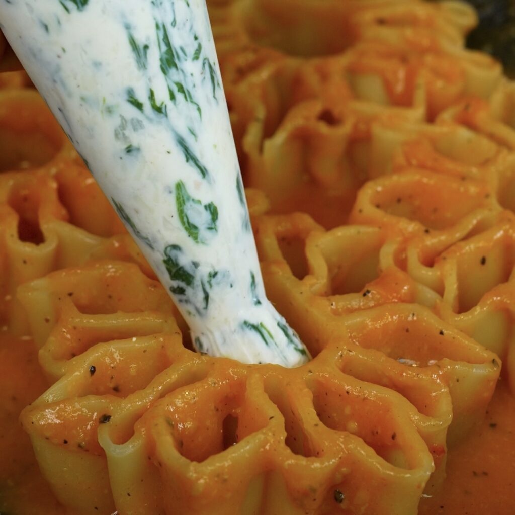 Filling the larger cavities of I Soli di Capri pasta with the four-cheese and spinach filling.