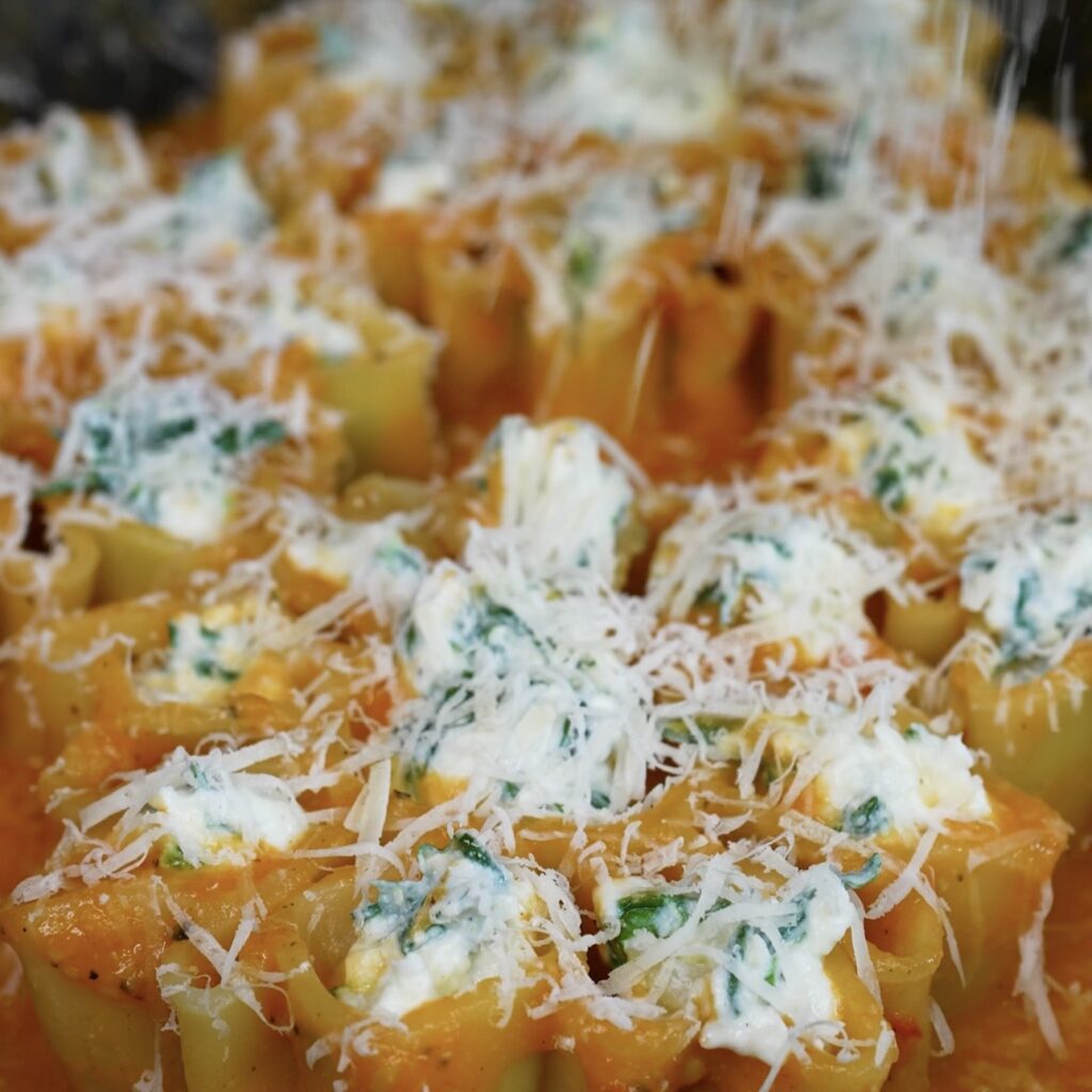Sprinkling grated Parmesan over the filled pasta before baking.