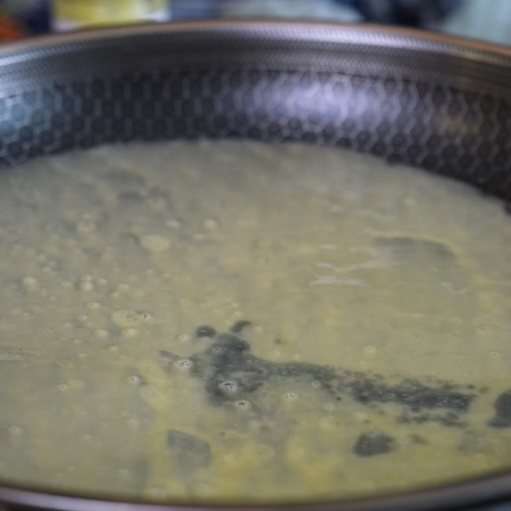 Egg-coated rice paper sheet cooking in a frying pan for a redcurrant rice paper pancake.