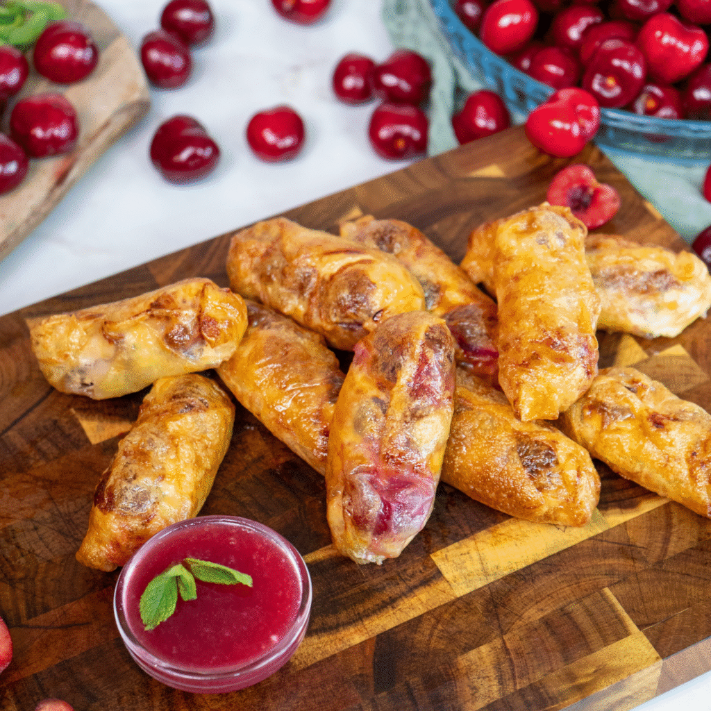 Cherry Ricotta Rice Paper Dumplings served on a wooden board with homemade cherry sauce.