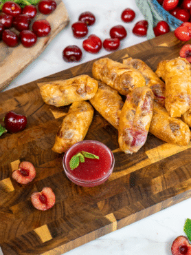 Cherry Ricotta Rice Paper Dumplings served on a wooden board with homemade cherry sauce.