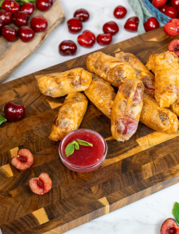 Cherry Ricotta Rice Paper Dumplings served on a wooden board with homemade cherry sauce.