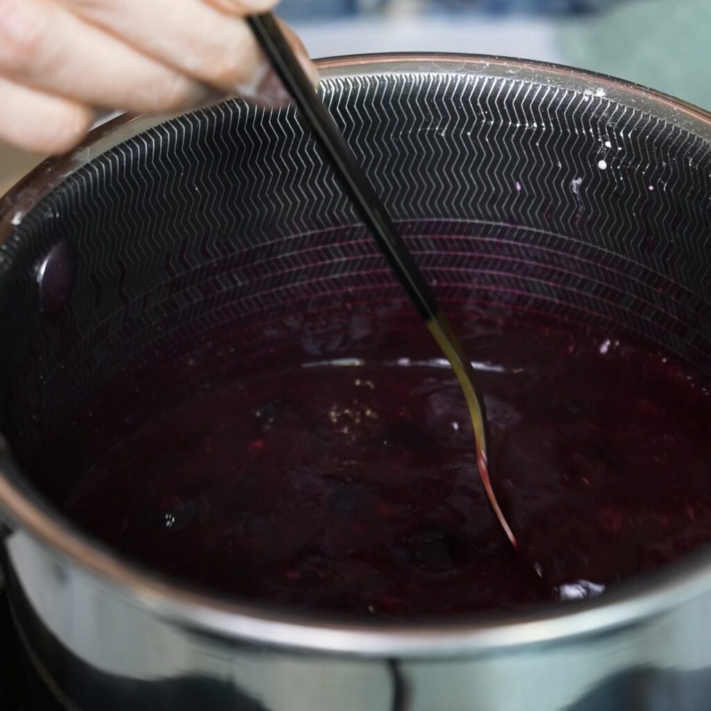 Blueberry sauce cooking in a small saucepan with blueberries, honey, cornflour and water.
