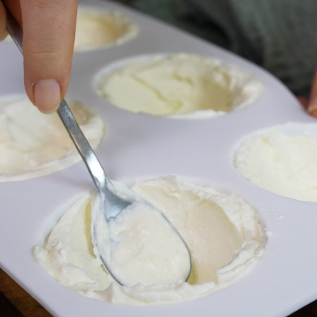 Silicone mould cavities being filled with a smooth cottage cheese mixture.