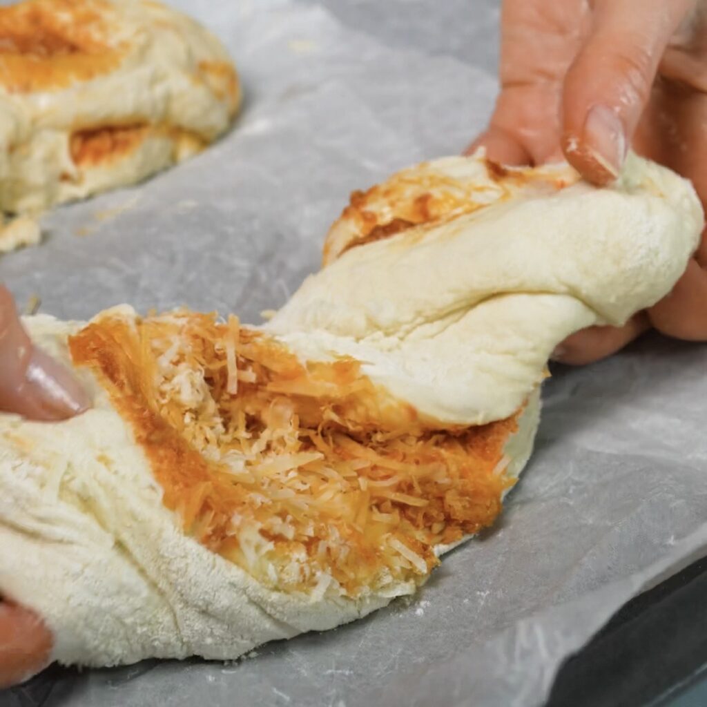 Twisted pesto and Parmesan baguettes being placed on a baking tray lined with baking parchment.