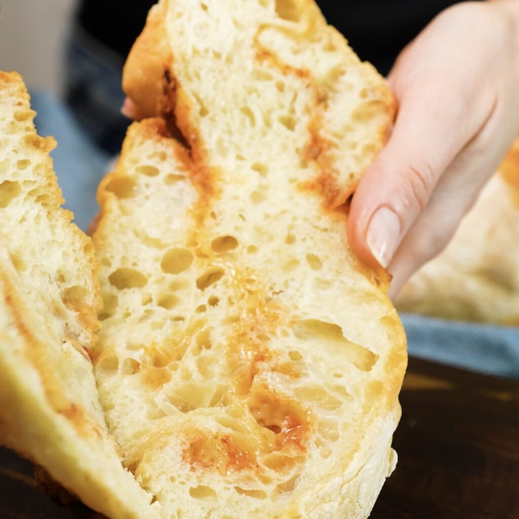 Pesto and Parmesan twisted baguette sliced lengthwise to reveal its light, airy crumb.