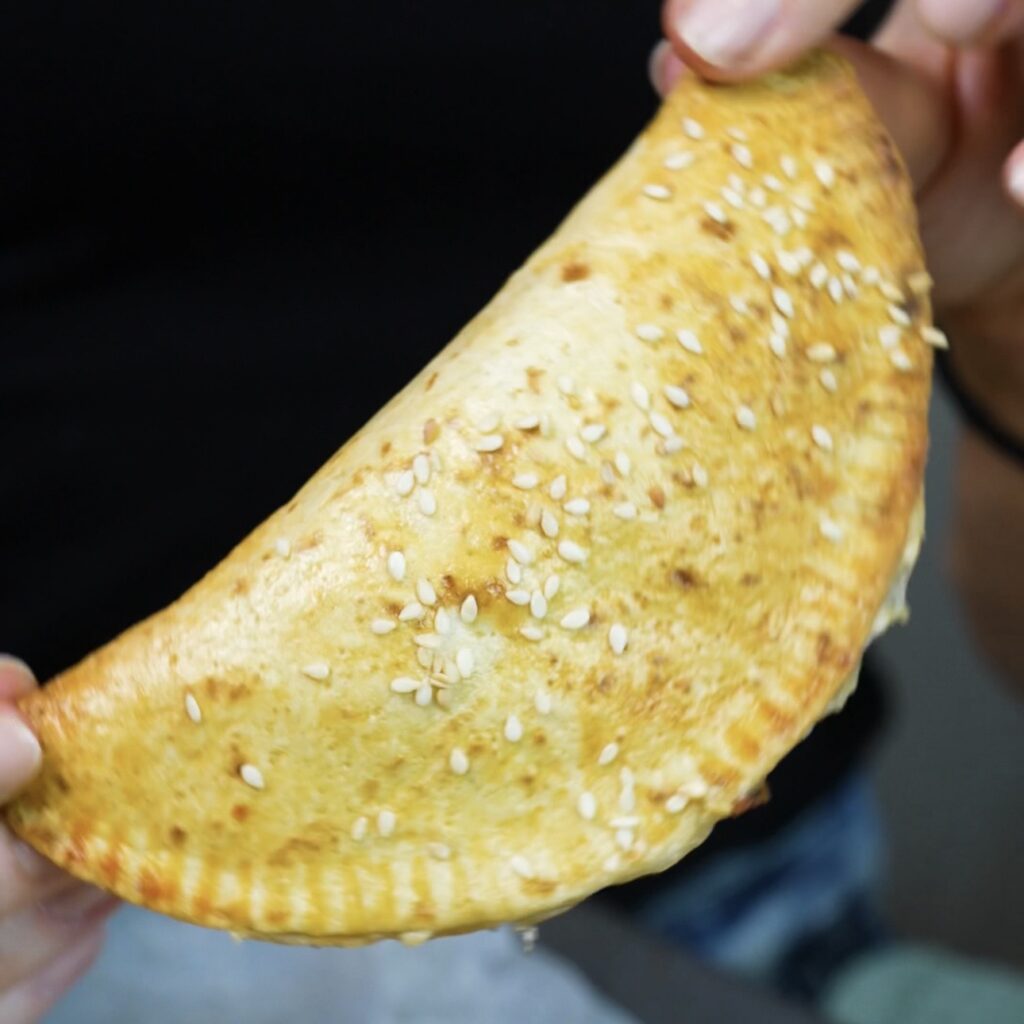 Hands holding one freshly baked Cheesy Chicken Tortilla Pocket.