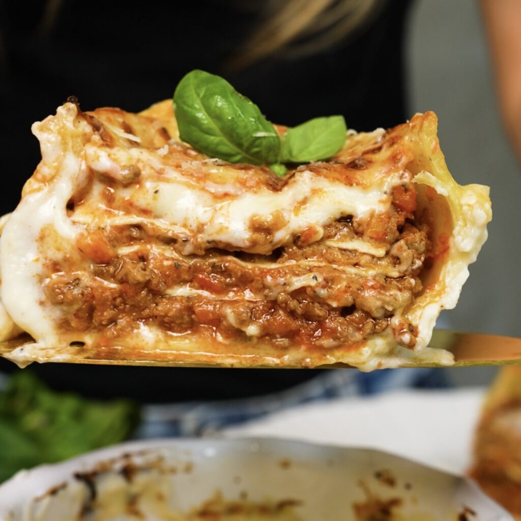 Stuffed Caccavelle pasta sliced in half to reveal layers of lasagna, beef ragù and creamy béchamel sauce.