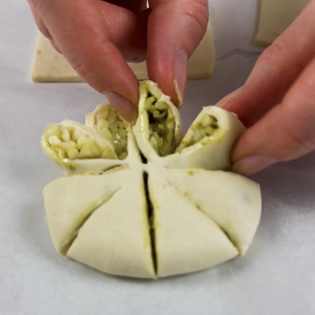 Twisting the cut sections of puff pastry to form flower-like petals