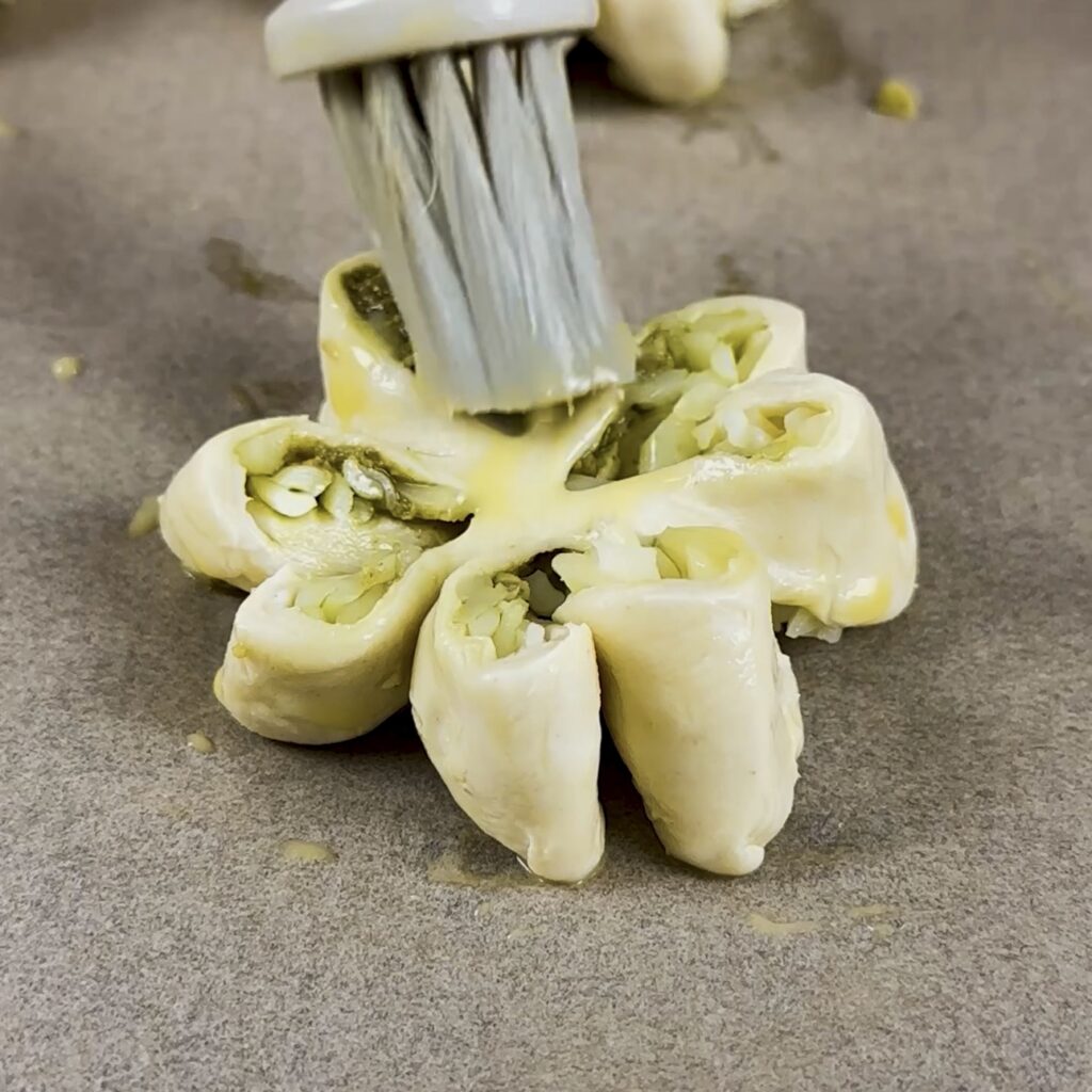 Brushing the shaped puff pastry with egg wash before baking