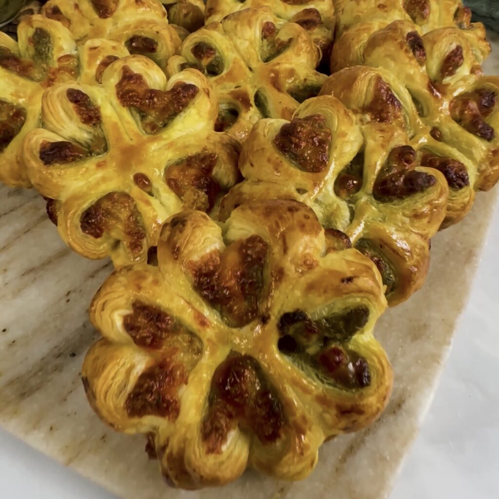 Pesto Mozzarella Puffs served on a marble board with golden flaky pastry and melted cheese