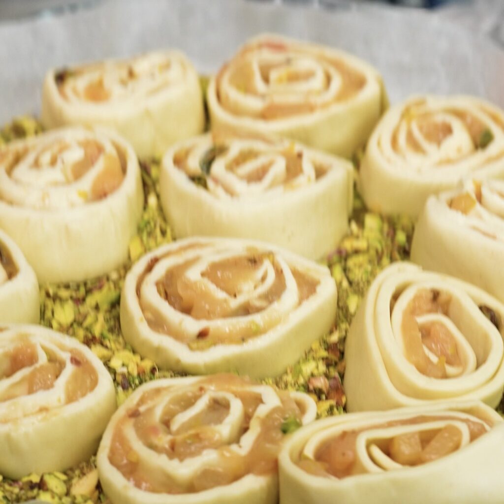 Adding the peach and pistachio puff pastry buns to the caramel and pistachio base.