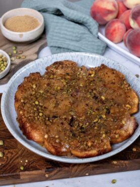 Sticky Peach and Pistachio Buns served on a plate with a glossy caramel and pistachio topping.