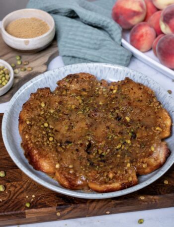 Sticky Peach and Pistachio Buns served on a plate with a glossy caramel and pistachio topping.